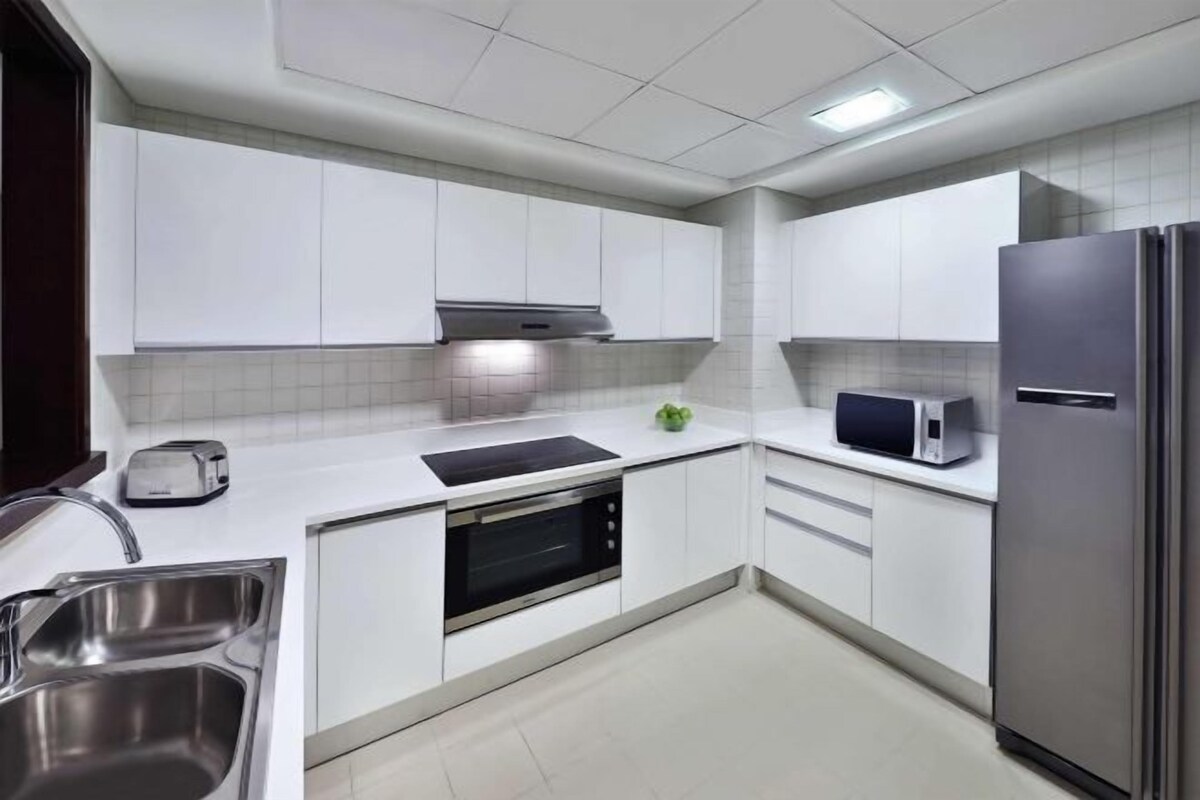A modern kitchen with white cabinets, stainless steel appliances, and a built-in oven.