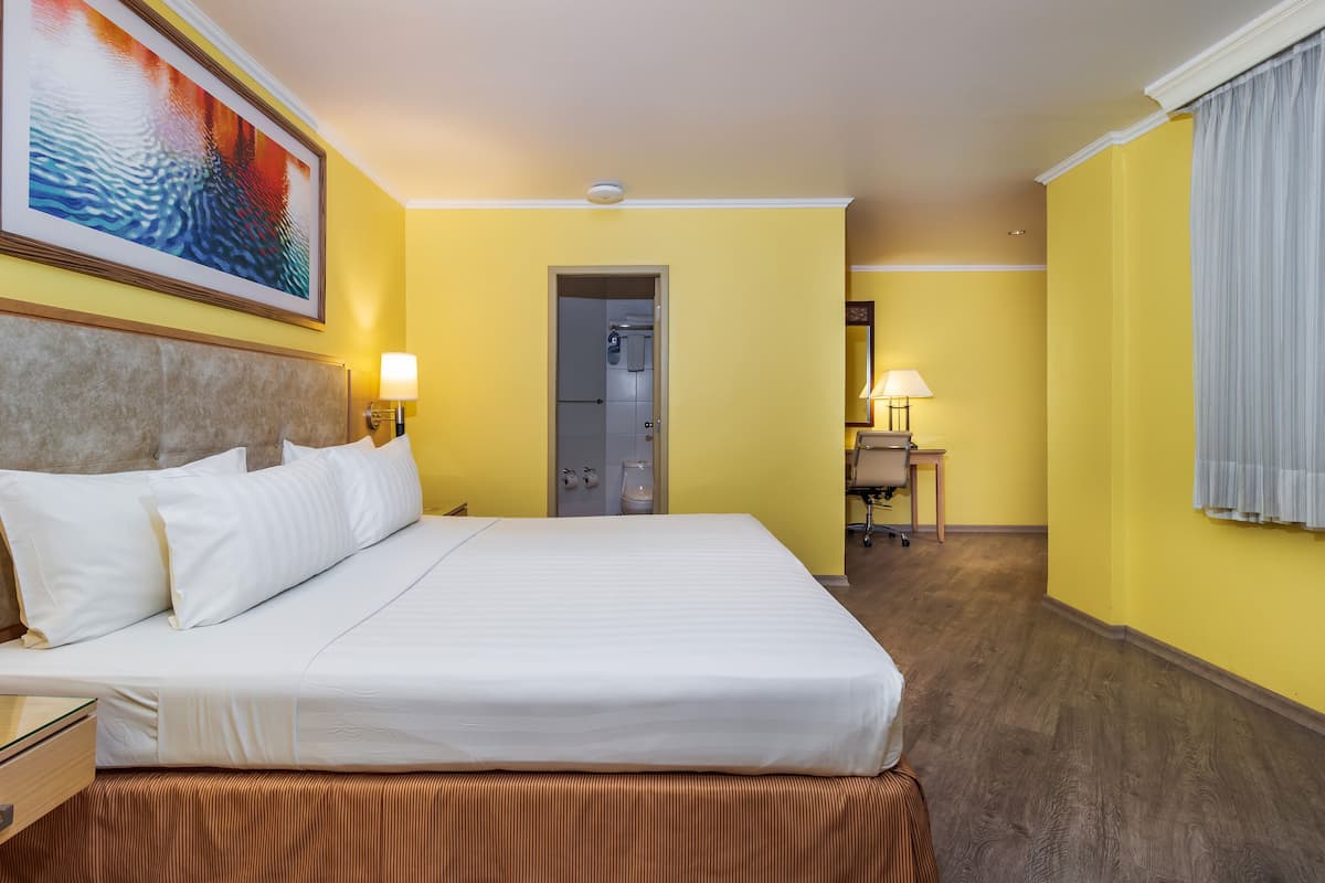Ein Hotelzimmer mit Bett, Nachttisch, Lampe und einem Bild an der Wand.