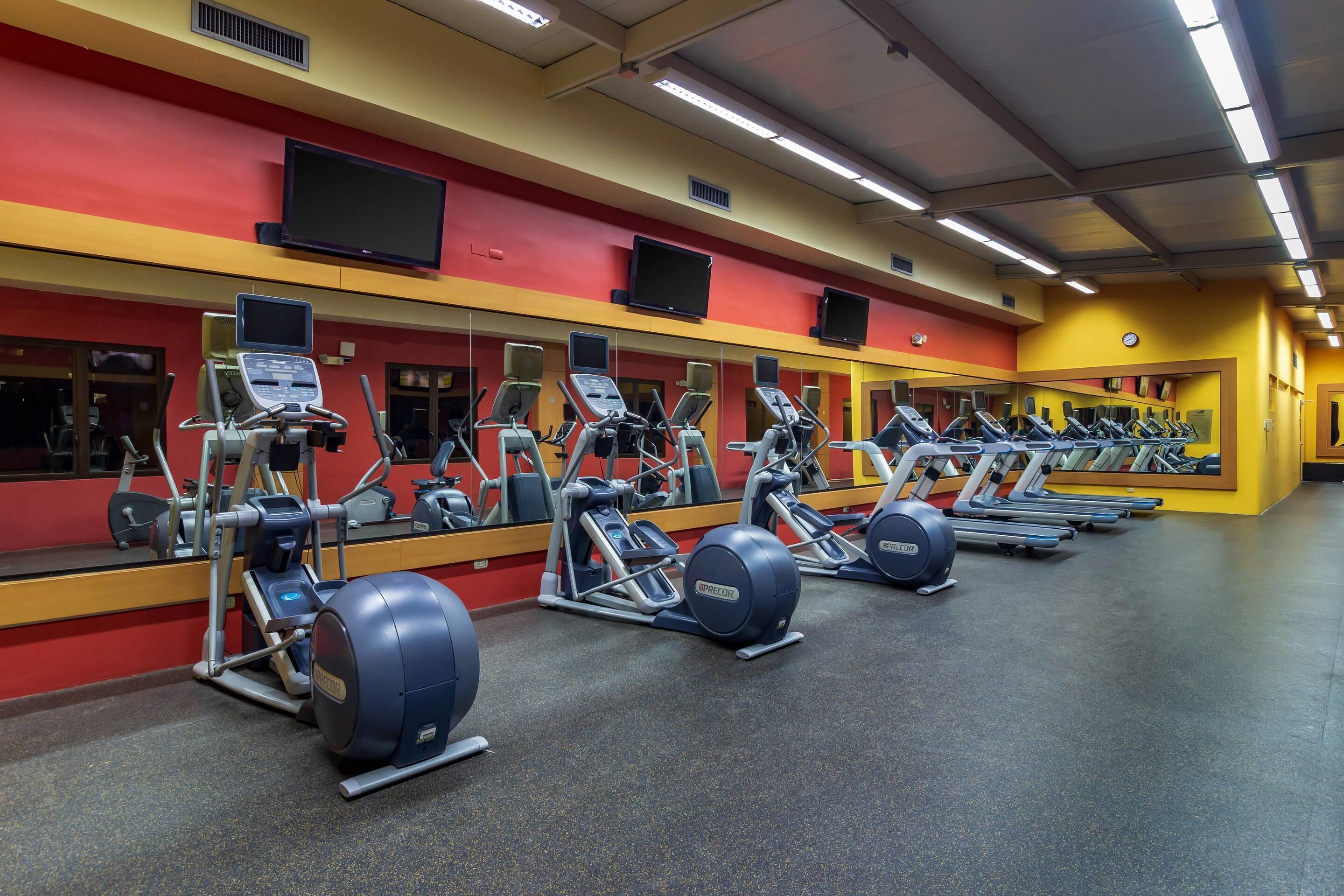 A gym with multiple treadmills, elliptical machines, and exercise bikes.