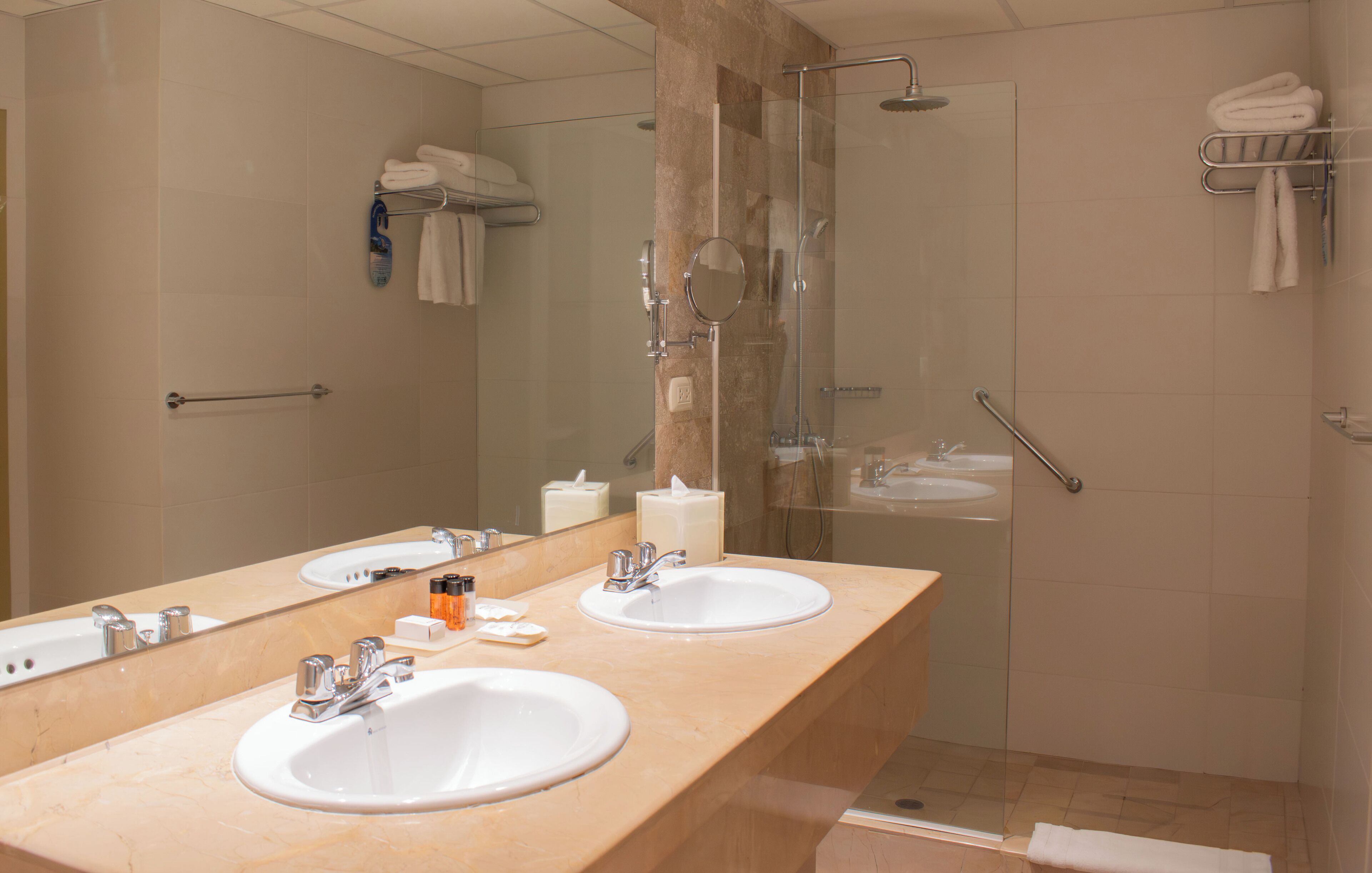 Une salle de bain avec deux lavabos, un grand miroir et une douche à parois de verre.