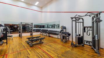A gym with exercise equipment, benches, and a mirrored wall.