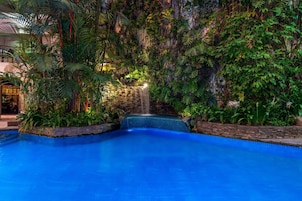 Una piscina interior con cascada, rodeada de exuberante vegetación tropical.