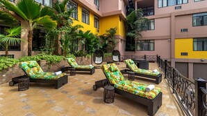 A rooftop lounge area with sun loungers, a small table, and a trash bin.