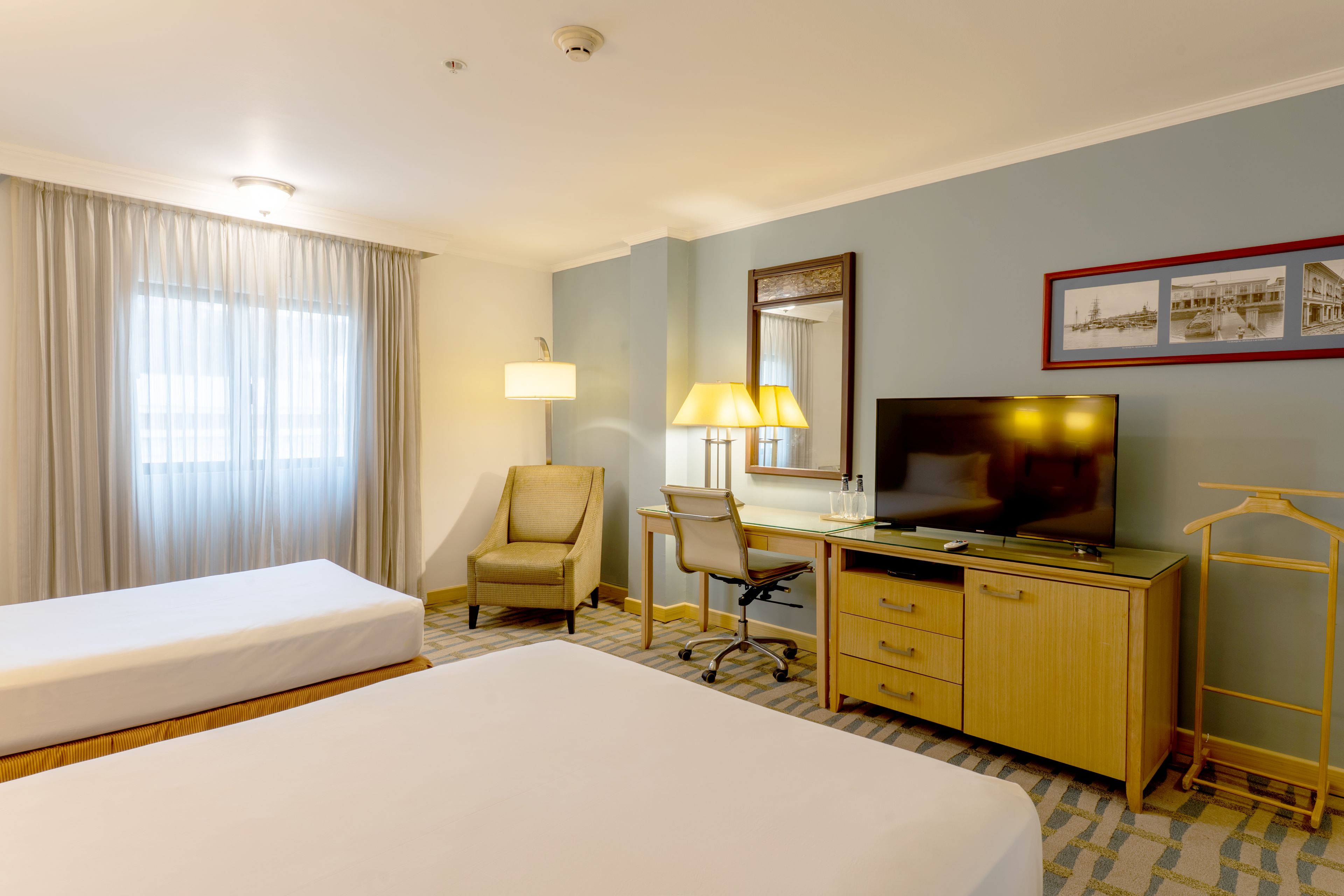 A hotel room with a bed, desk, chair, TV, and a mirror.
