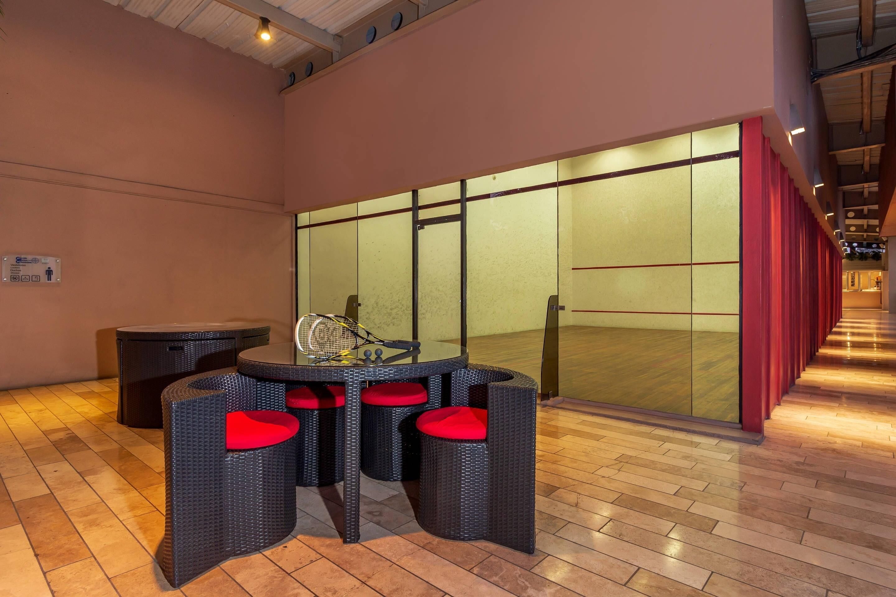 Ambiente interno moderno con tavolo e sedie, una racchetta da tennis e un divisorio in vetro.