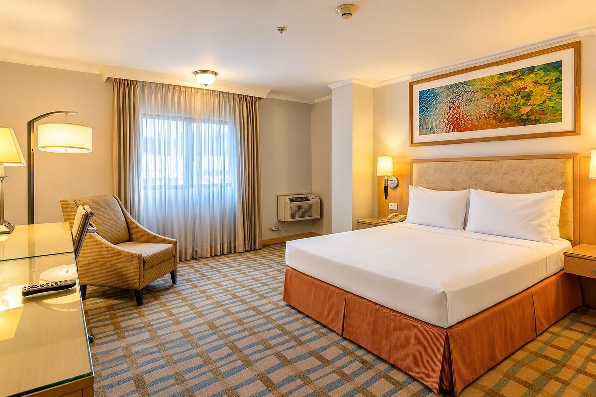 Een hotelkamer met een bed, een stoel, een bureau en een schilderij aan de muur.