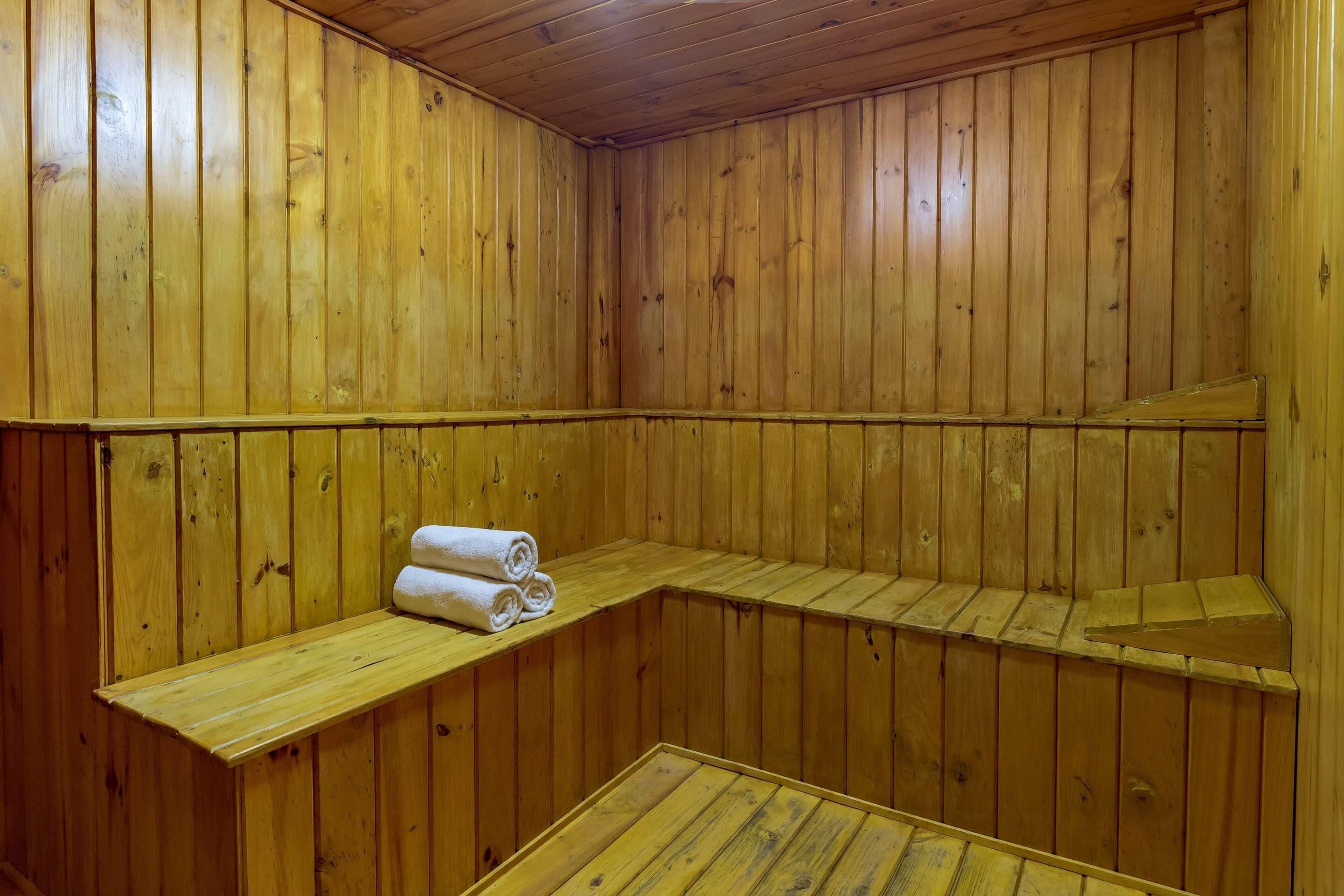 Una sauna de madera con bancos y un estante con toallas enrolladas.