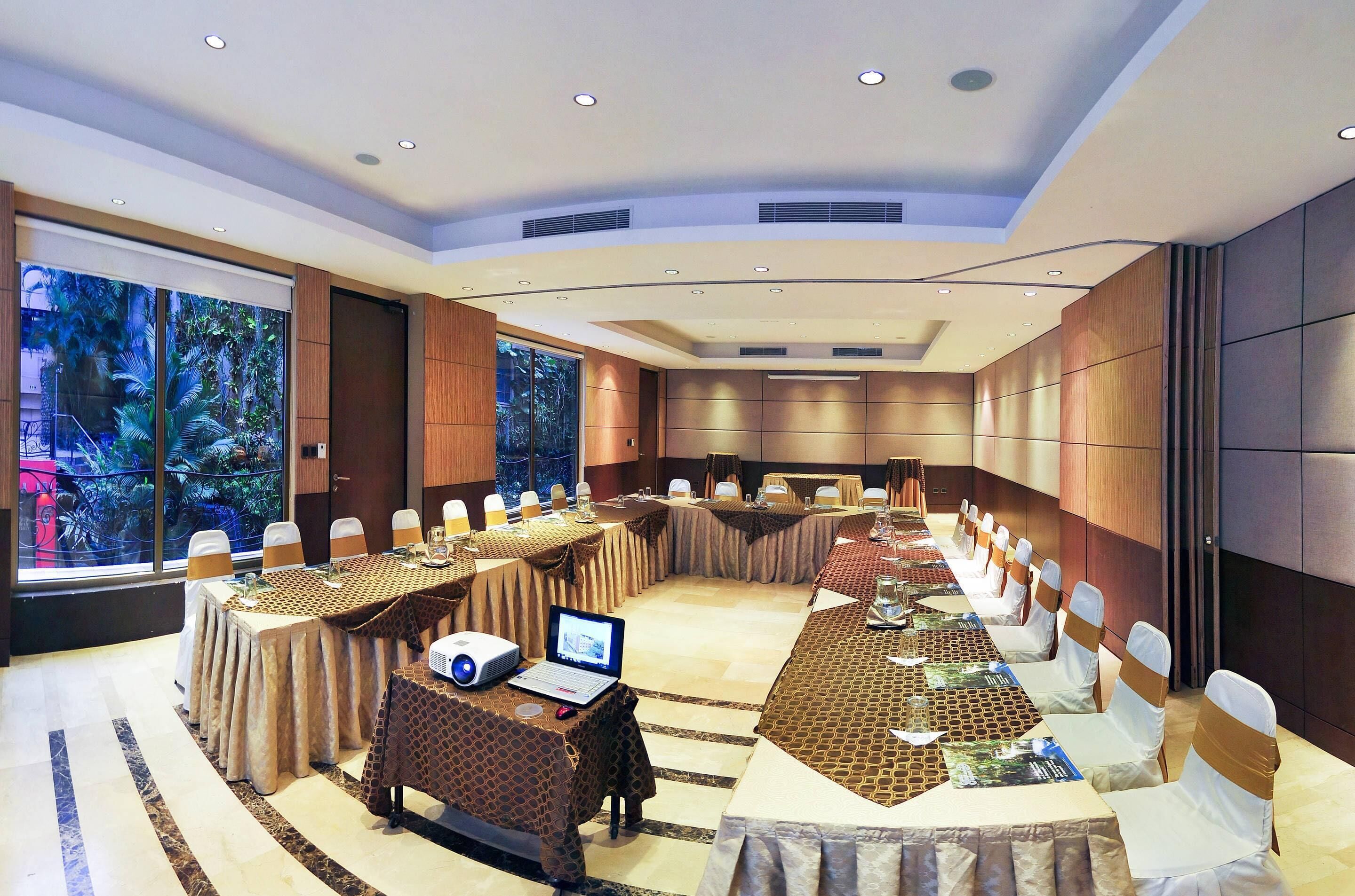 Un salón de conferencias con una mesa larga, sillas y una computadora portátil.