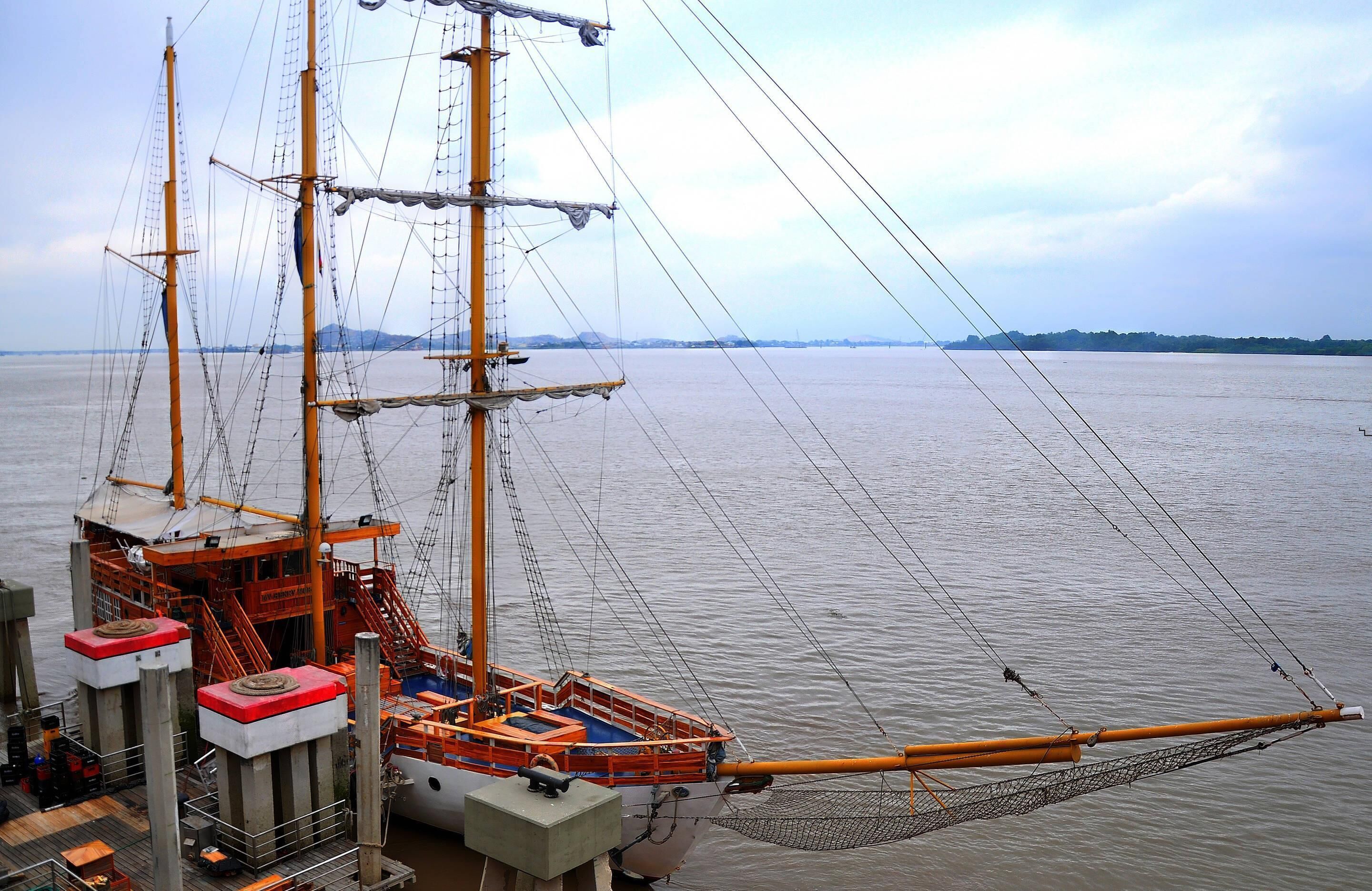 A large sailing ship docked at a pier with visible masts and rigging.