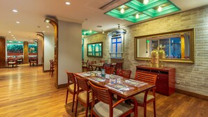 A restaurant with wooden flooring, red chairs, and a brick wall.