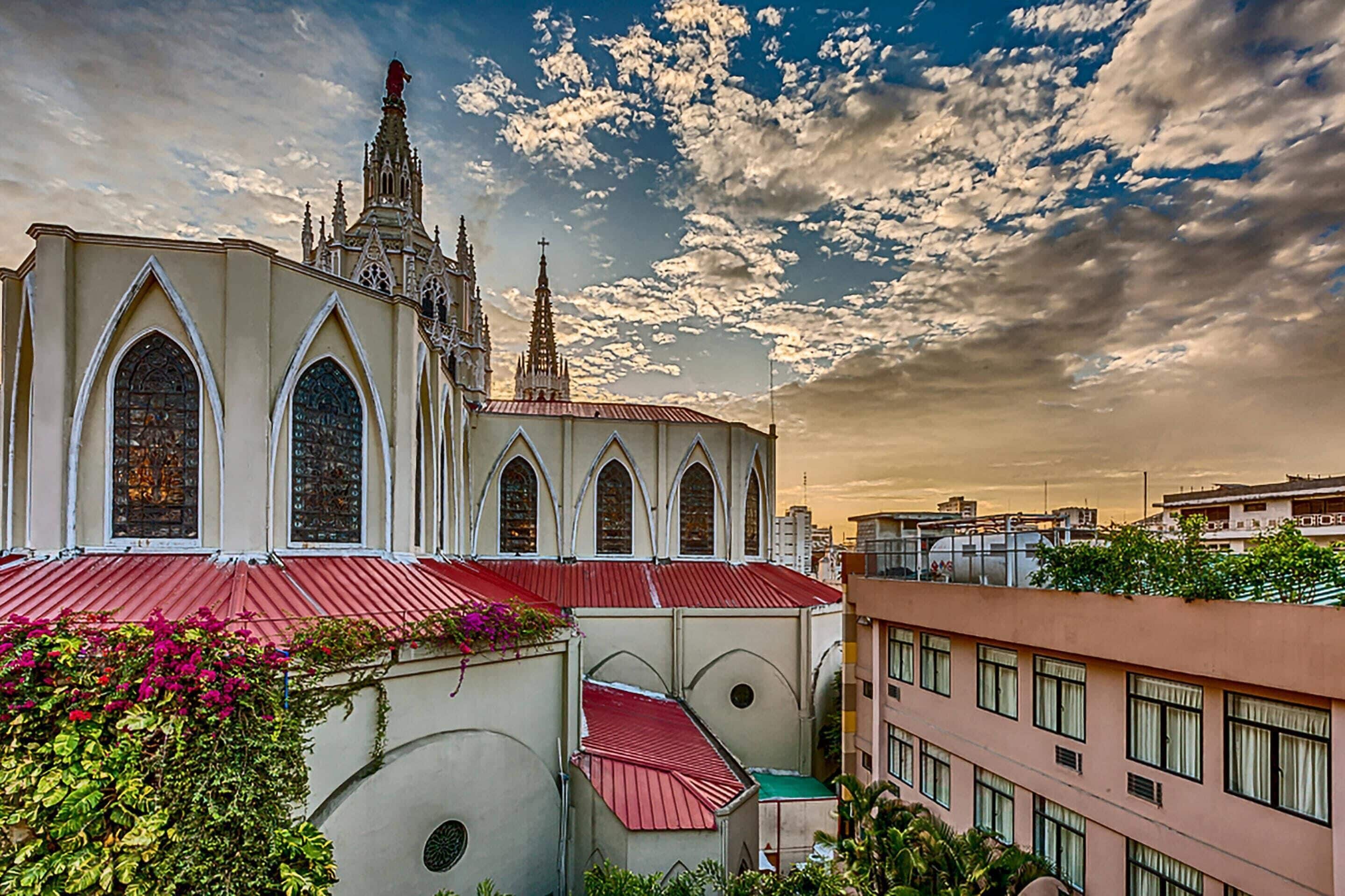 Una iglesia de techo rojo y arquitectura gótica, rodeada de edificios modernos.