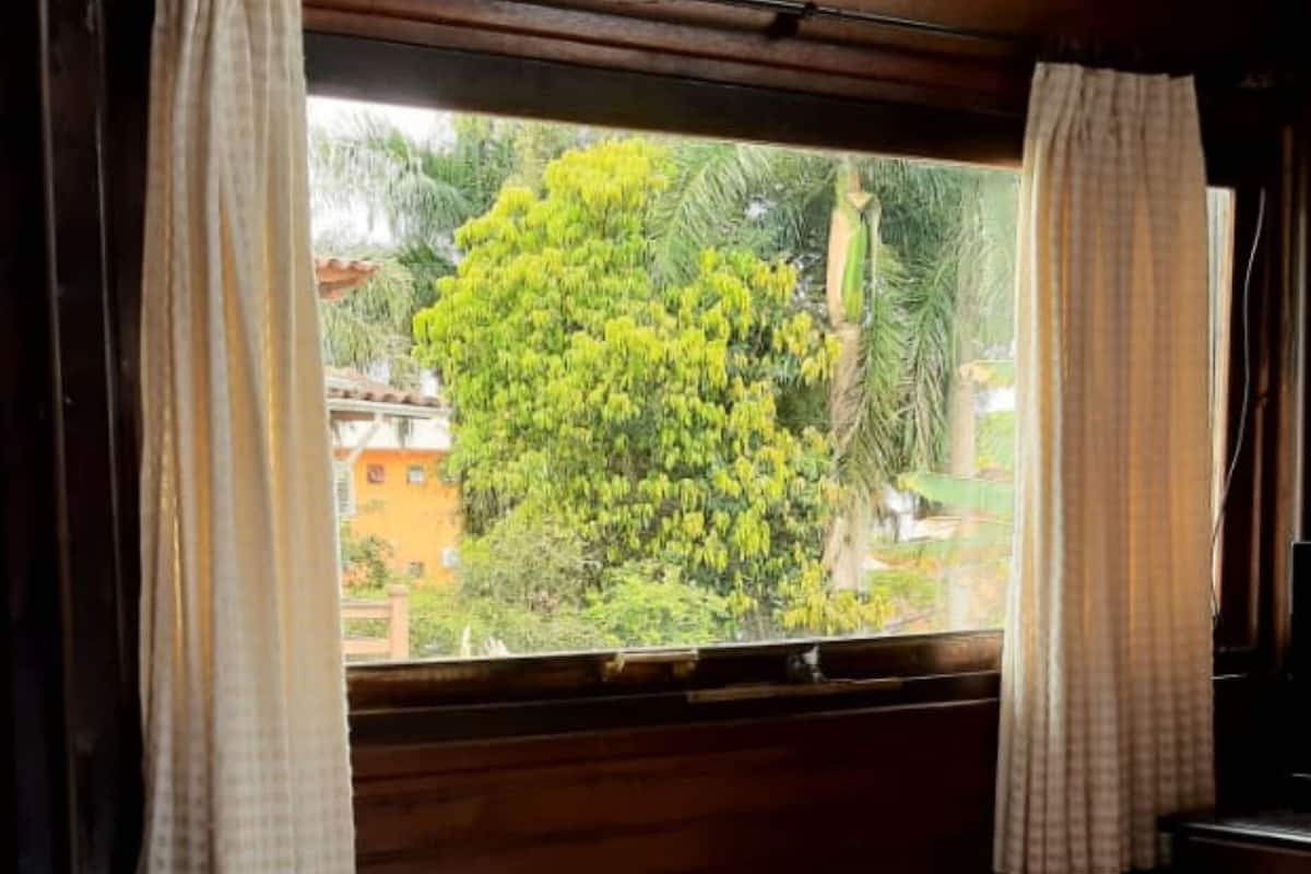 A room with a bed, wooden headboard, and a window with curtains.
