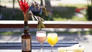 A table with a bottle, a glass of orange juice, a glass of milk, a plate with bread and a cake, and a plate with sliced bananas. - Hostel Sereia do Mar (Paraty)