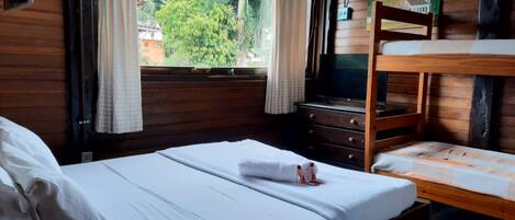A room with a bunk bed, a single bed, a dresser, and a television.