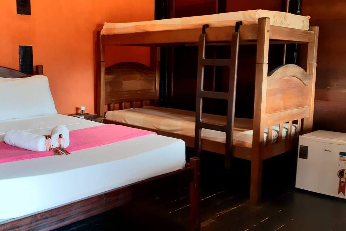 A bed with a wooden headboard, a bedside table, and a small refrigerator.