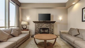 A modern living room with a stone fireplace, a flat-screen TV, and two sofas. - Best Western Plus Moose Jaw (Moose Jaw)