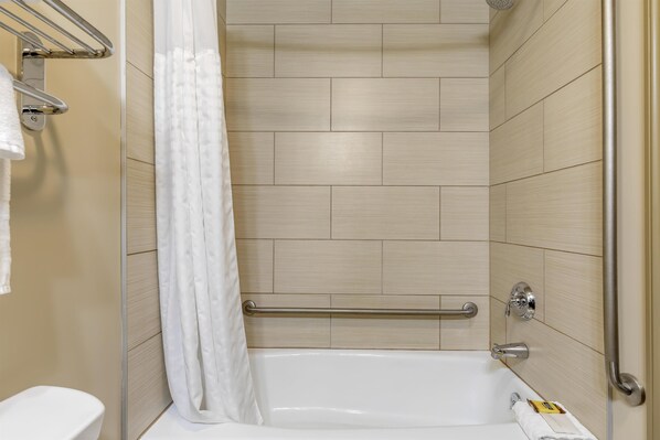 Un baño moderno con bañera, cortina de ducha y barandilla.