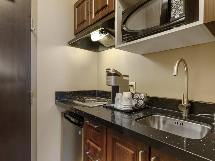 A modern kitchen with a stainless steel sink, a coffee maker, and wooden cabinets.