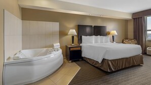 A hotel room with a large bed, a separate bathroom with a bathtub, two bedside lamps, and a window with curtains. - Best Western Plus Moose Jaw (Moose Jaw)