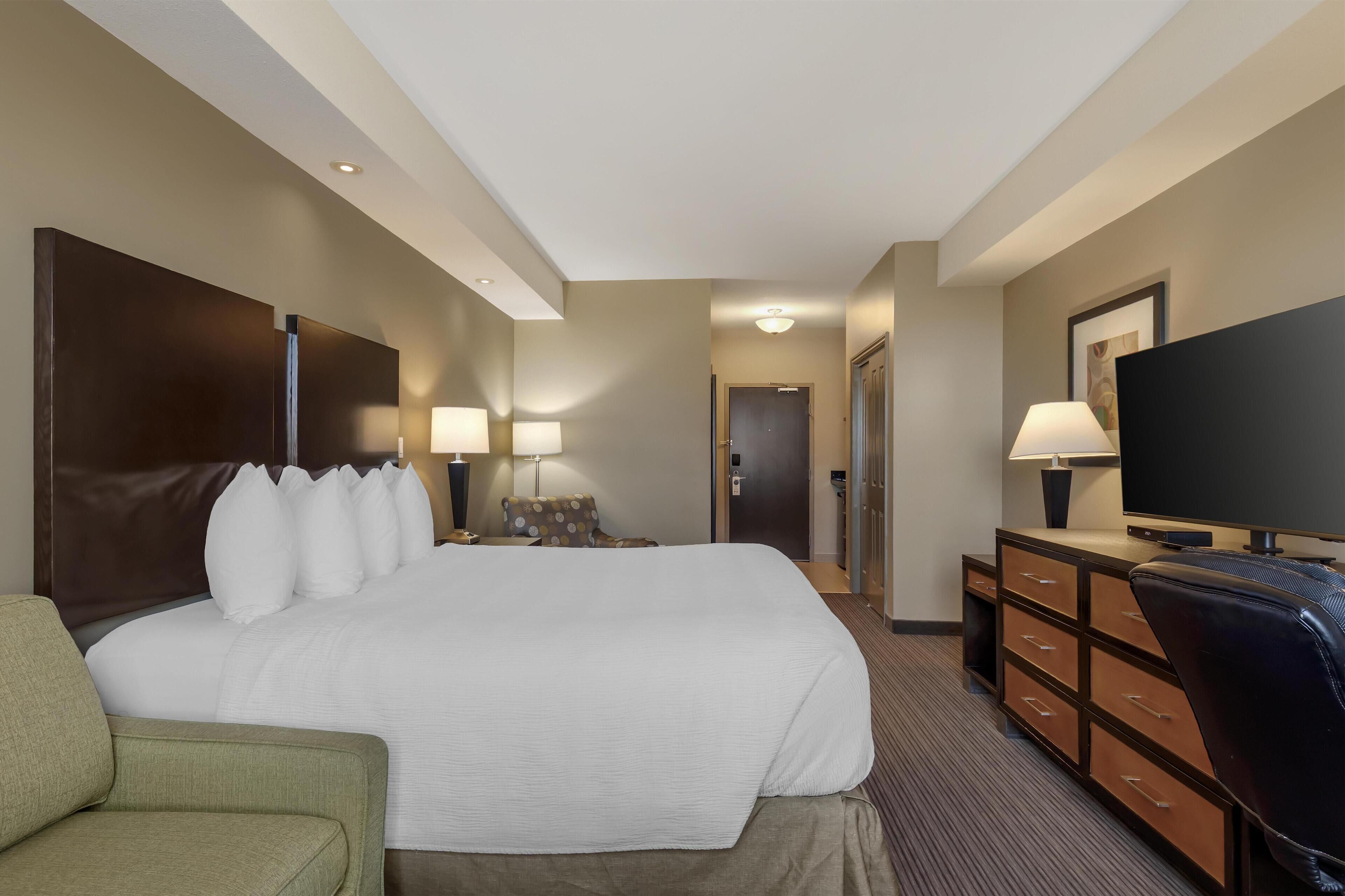 Habitación de hotel con una cama grande, televisión, escritorio con lámpara y una silla.