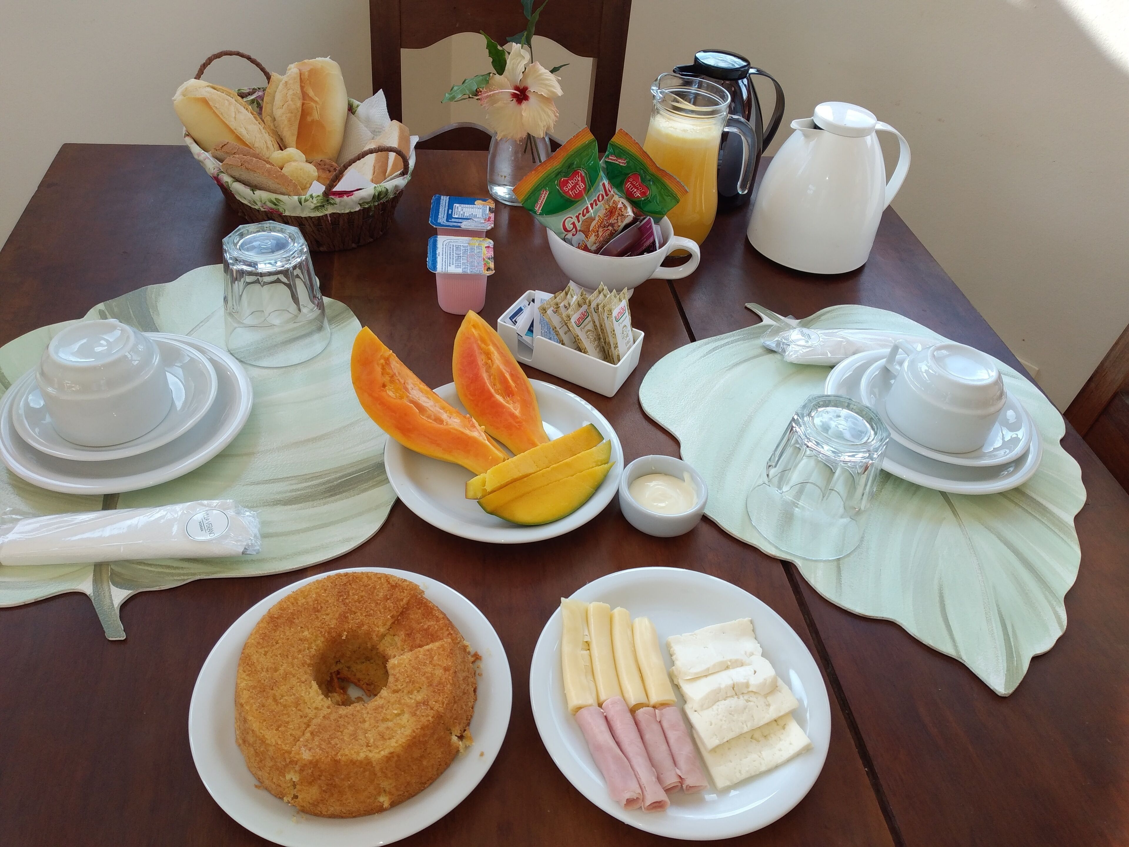 A breakfast table with various food items, including bread, fruit, and a cake.