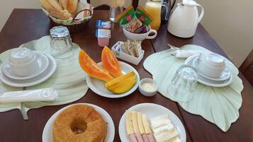 Una mesa de desayuno con diferentes alimentos, como pan, fruta y pastel.