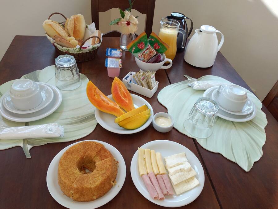 Una mesa de desayuno con diferentes alimentos, como pan, fruta y pastel.