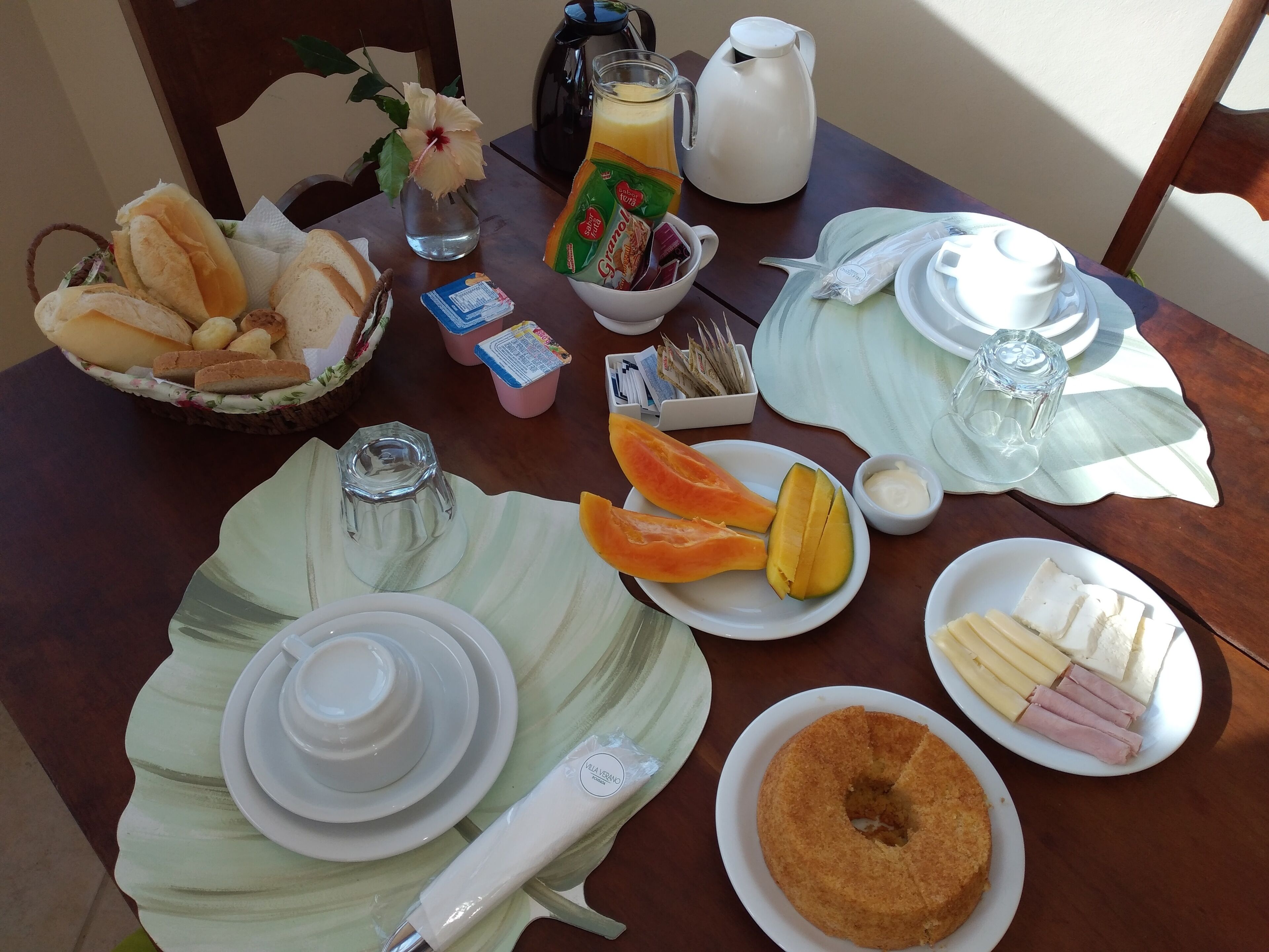 A breakfast table with bread, fruit, butter, and condiments.