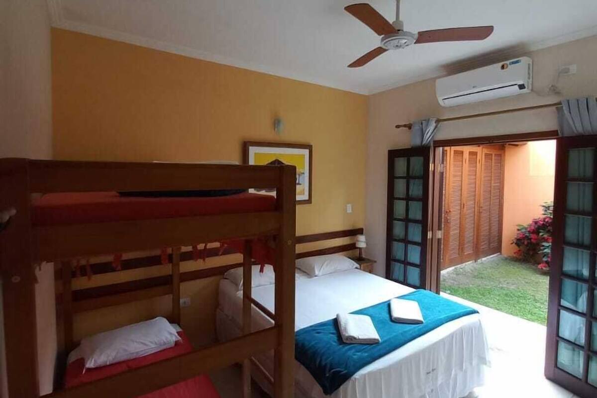 A room with bunk beds, a ceiling fan, an air conditioning unit, and a door leading to an outdoor area.