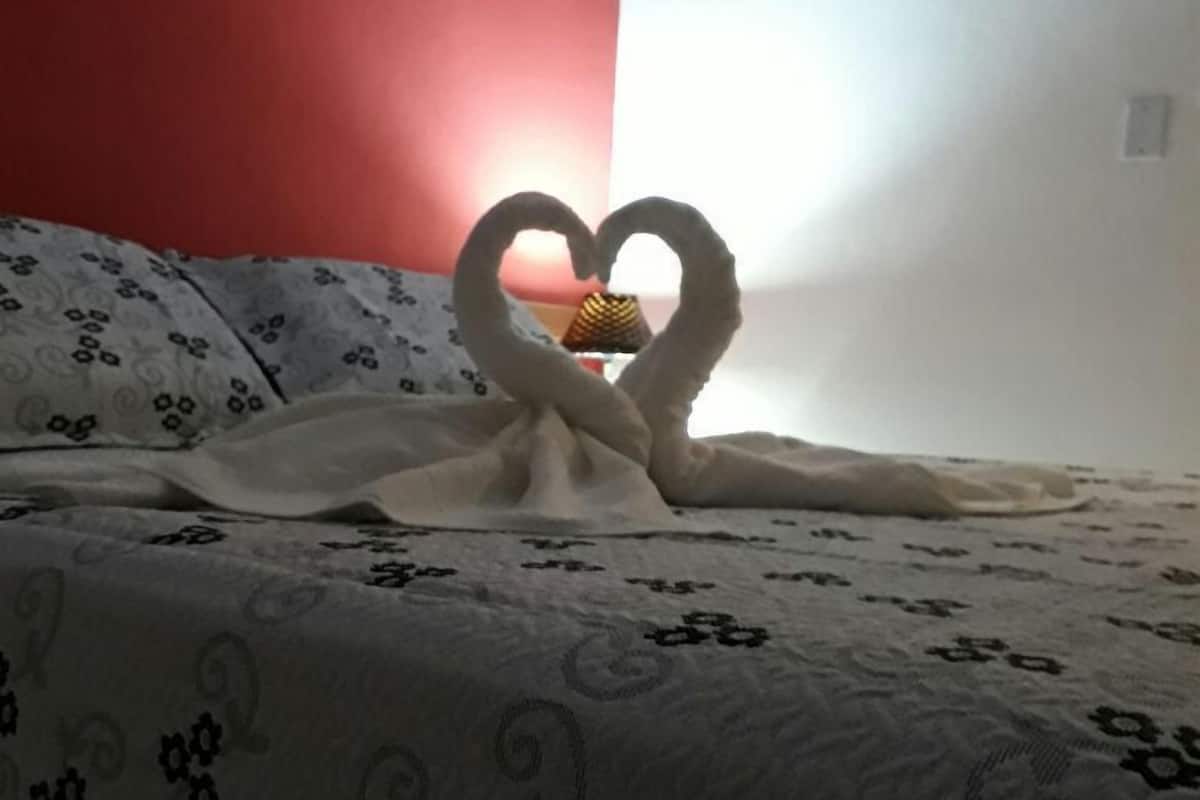 A bed with a heart-shaped towel arrangement.
