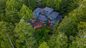 Ein mehrstöckiges Haus, umgeben von dichtem Wald.