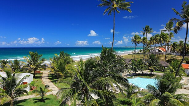 A resort with a pool, palm trees, and a view of the ocean. - Village Porto de Galinhas (Ipojuca)
