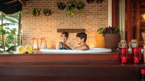 A couple in a hot tub with a brick wall, potted plants, and candles. - Village Porto de Galinhas (Ipojuca)