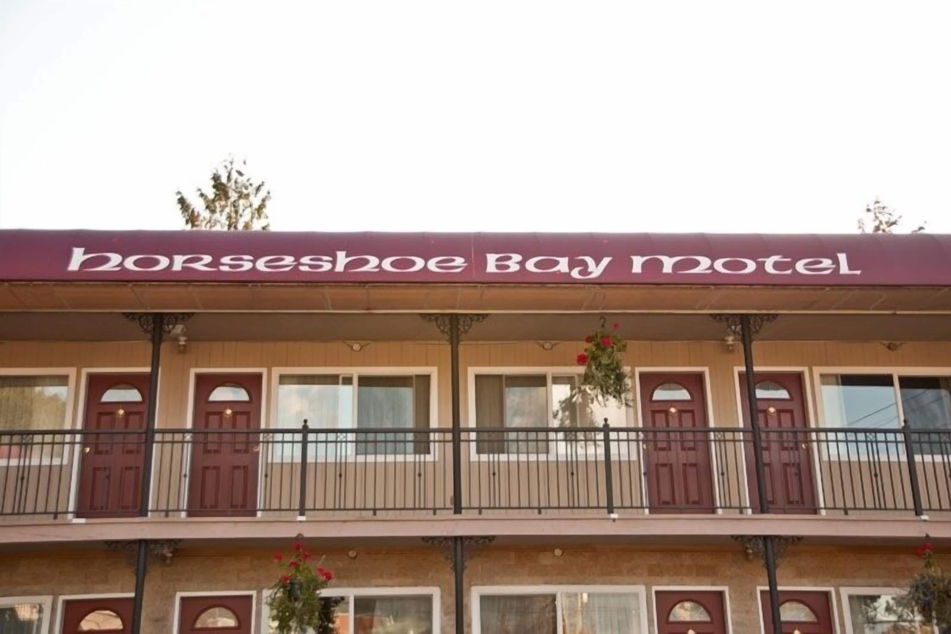 A motel with a sign reading "Horseshoe Bay Motel." It features a balcony with railings and multiple windows.