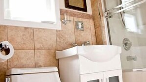 Une salle de bain équipée de toilettes, d’un lavabo, d’un miroir et d’une douche.