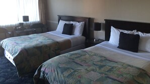 Une chambre d’hôtel avec deux lits, un bureau, une chaise et une lampe.