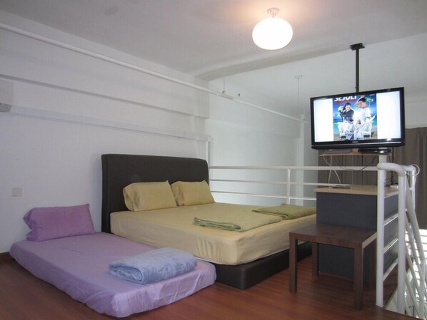 A room with a bed, a smaller bed or couch, a television, and a staircase.