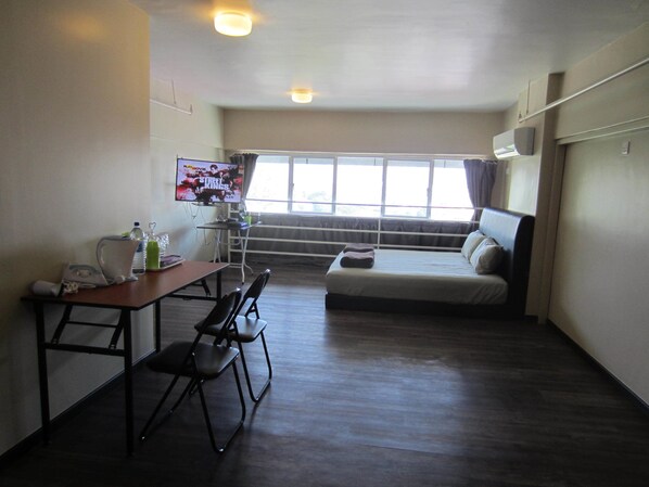 Una habitación pequeña con cama, escritorio y televisor.