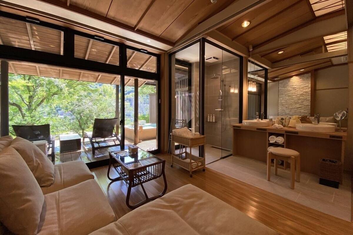 Een modern interieur met een bank, een douche met glazen wand en een keukenhoek.