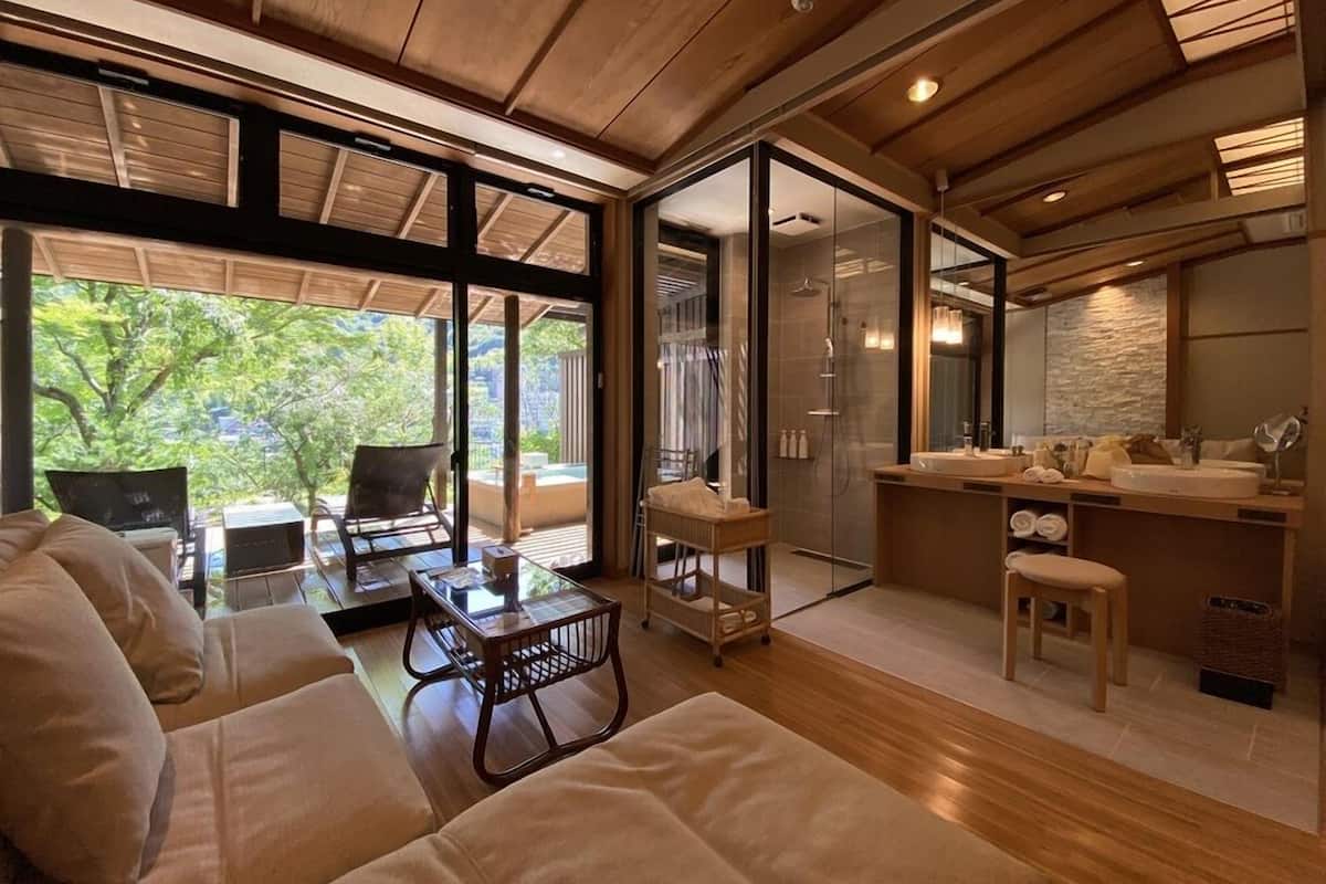 A modern interior with a sofa, a glass-enclosed shower, and a kitchen area.