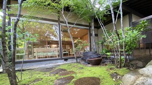 Een traditionele Japanse tuin met een vijver met koi karpers, bemoste stenen en een houten brug.