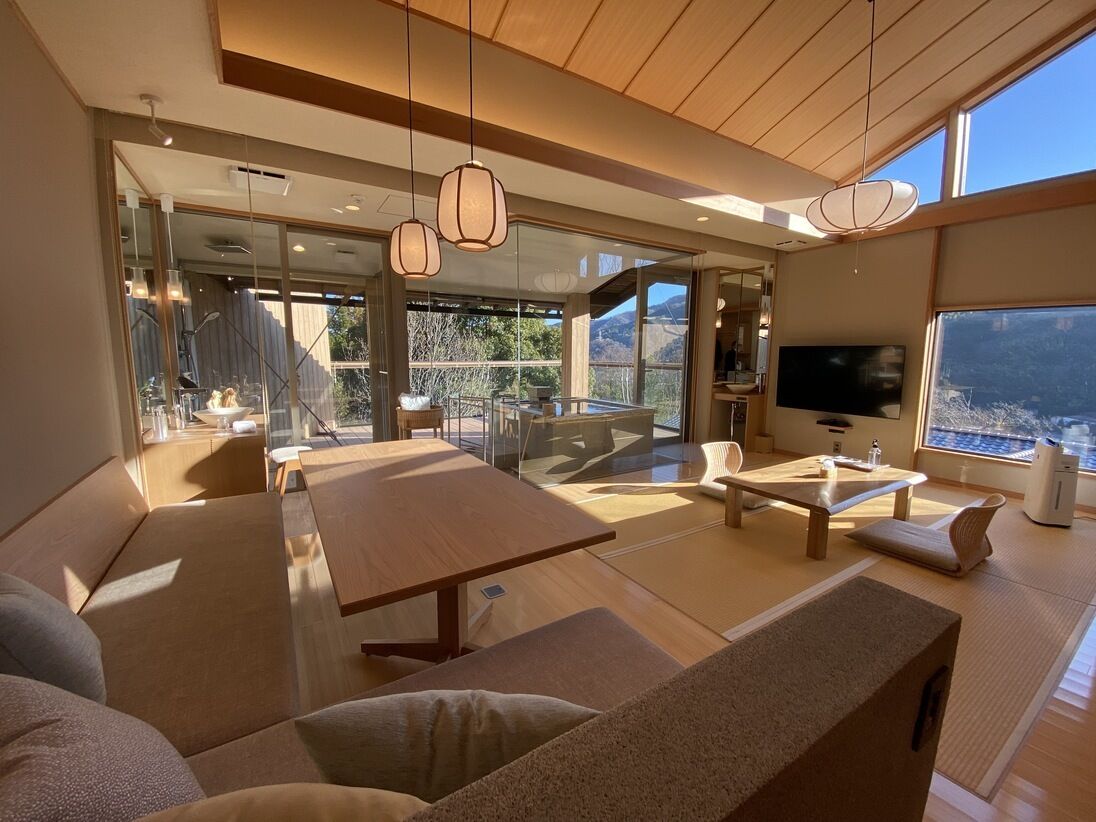 A modern living room with a large wooden table, sofas, and a television.
