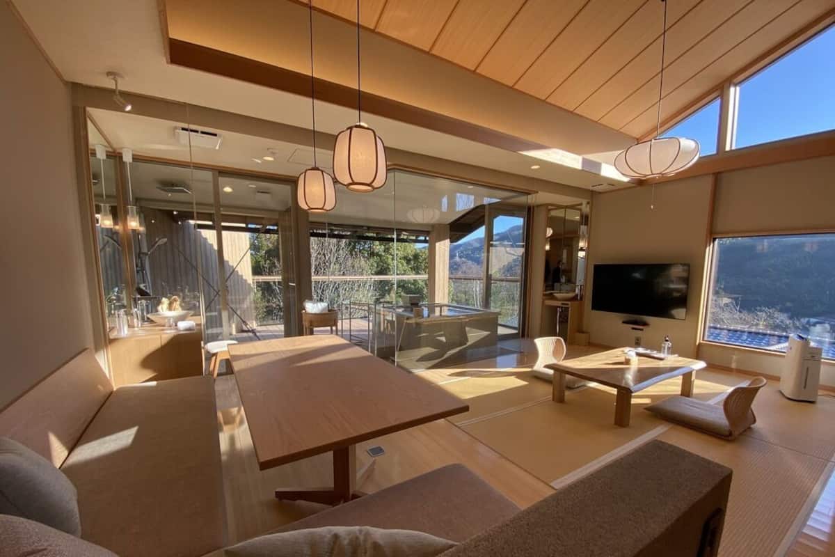 Een moderne woonkamer met een grote houten tafel, banken en een televisie.