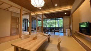 Een traditionele Japanse kamer met tatami vloerbedekking, een lage houten tafel en een televisie op een plank.