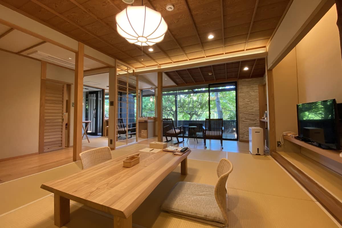 Een traditionele Japanse kamer met tatami vloerbedekking, een lage houten tafel en een televisie op een plank.