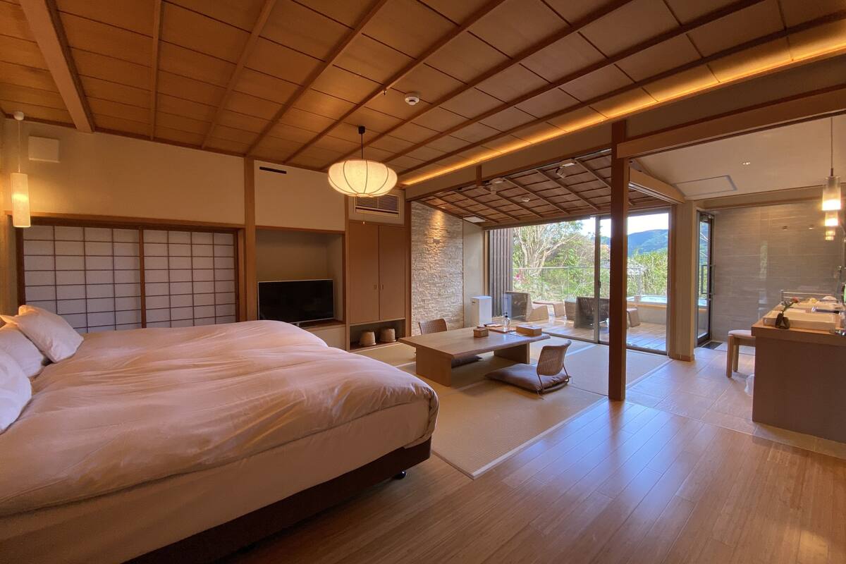 Een moderne hotelkamer met een groot bed, een televisie, een zithoek en een badkamer.