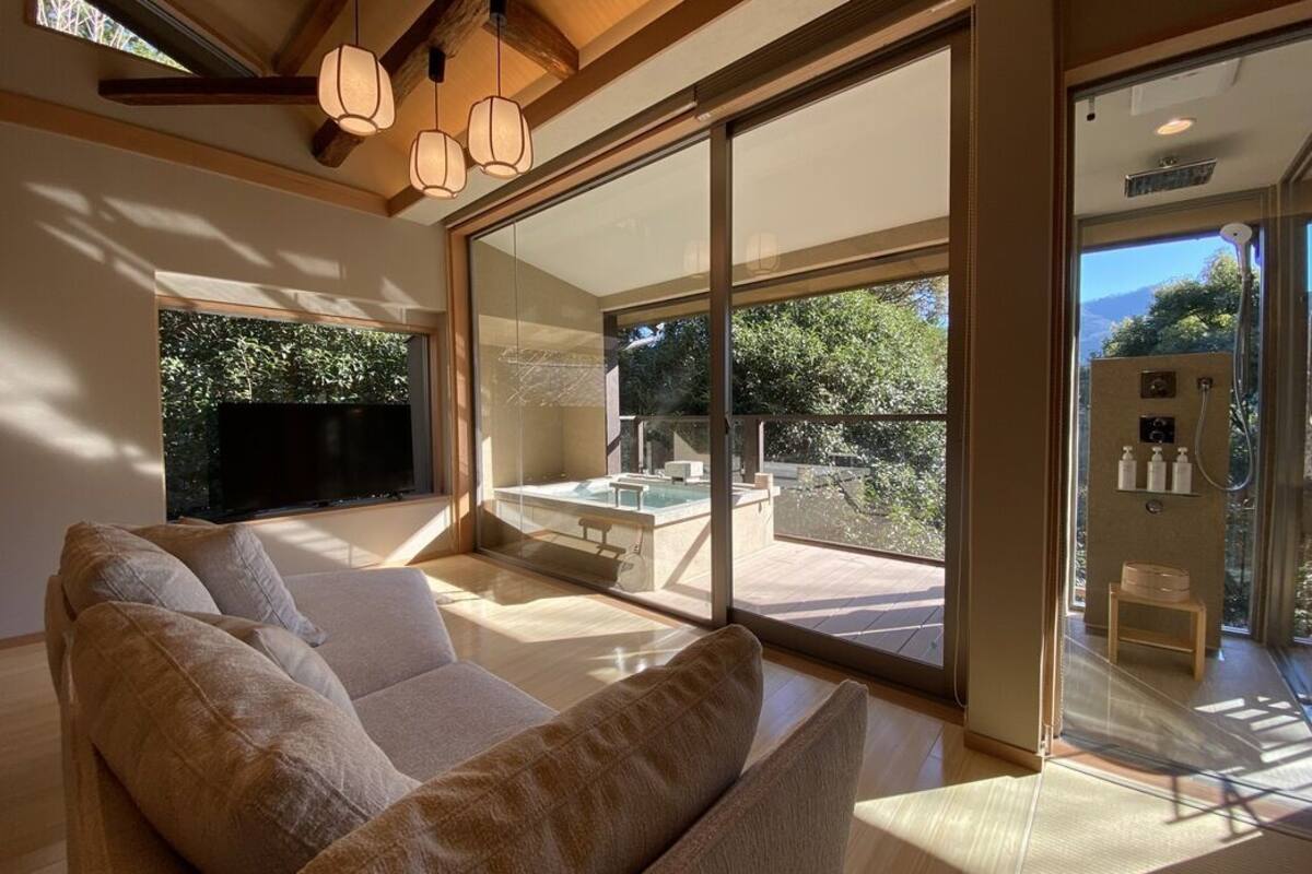Een moderne woonkamer met een grote bank, een glazen balkon en een televisie.