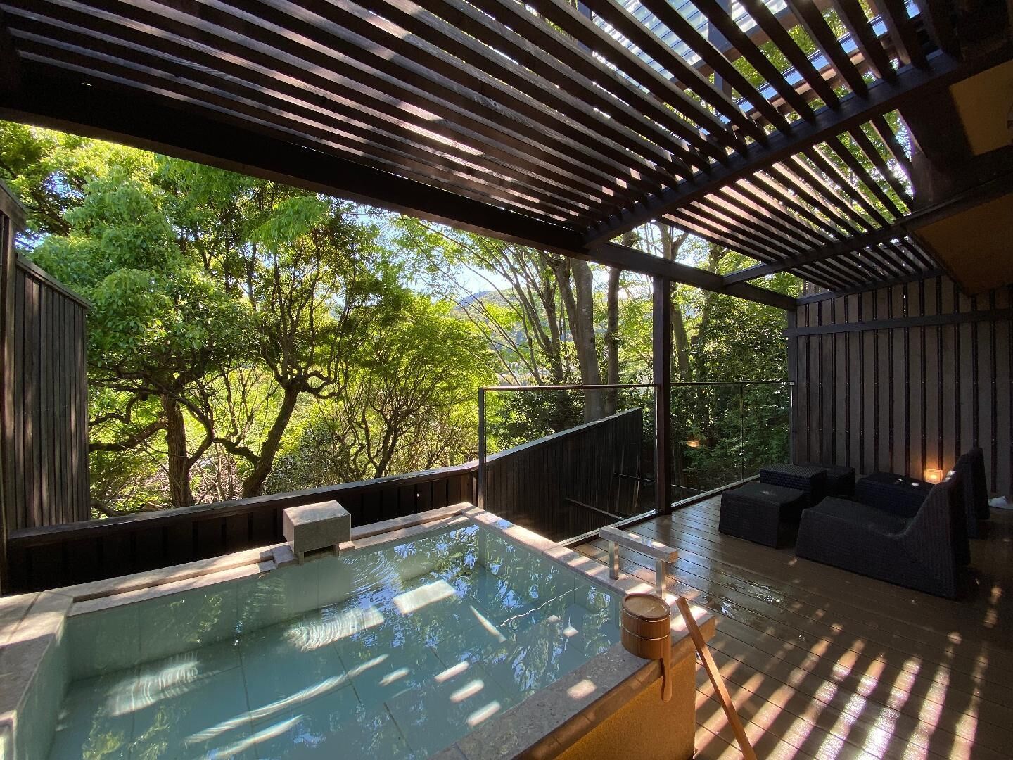 Un área moderna de hidromasaje al aire libre con vista a árboles y una terraza de madera.