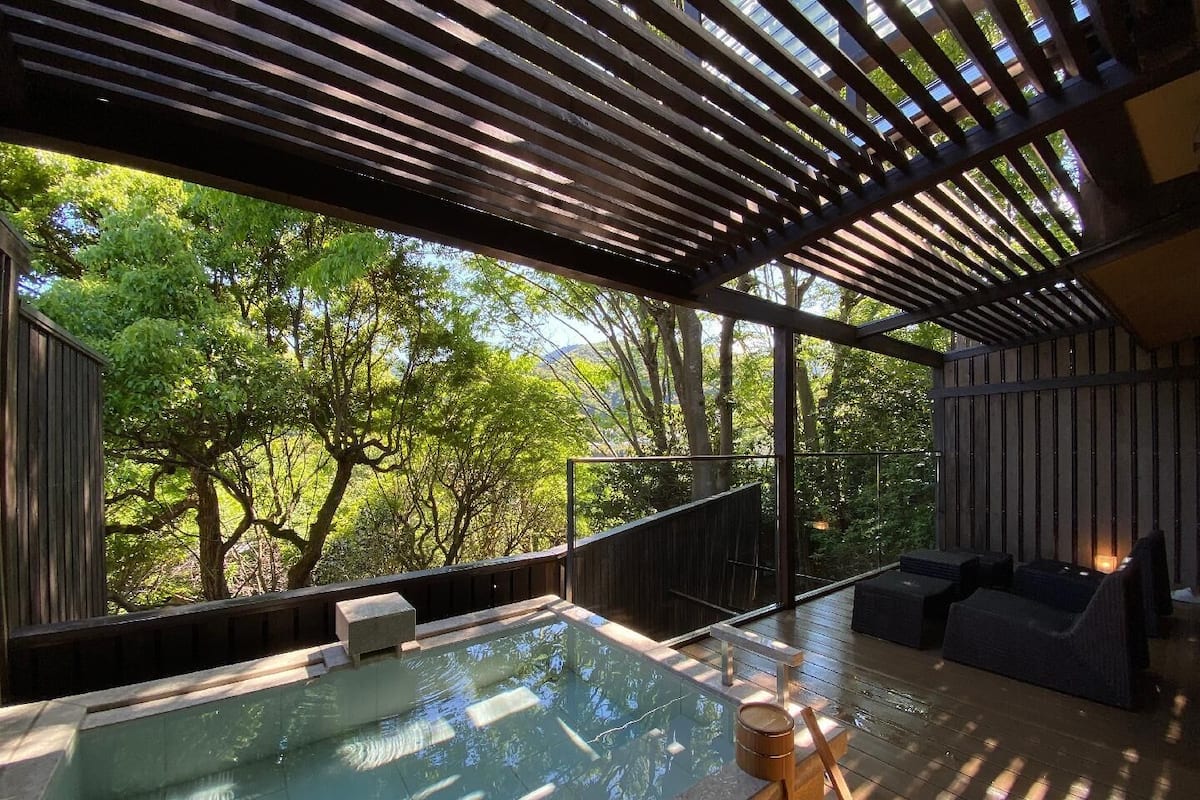 Un área moderna de hidromasaje al aire libre con vista a árboles y una terraza de madera.