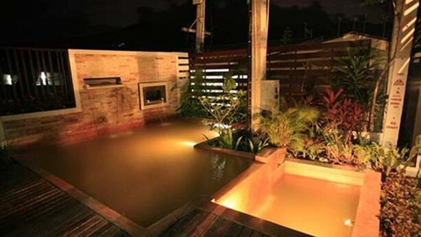 A rooftop pool area with a wooden deck and a small water feature. - CS Park (Koh Samui)